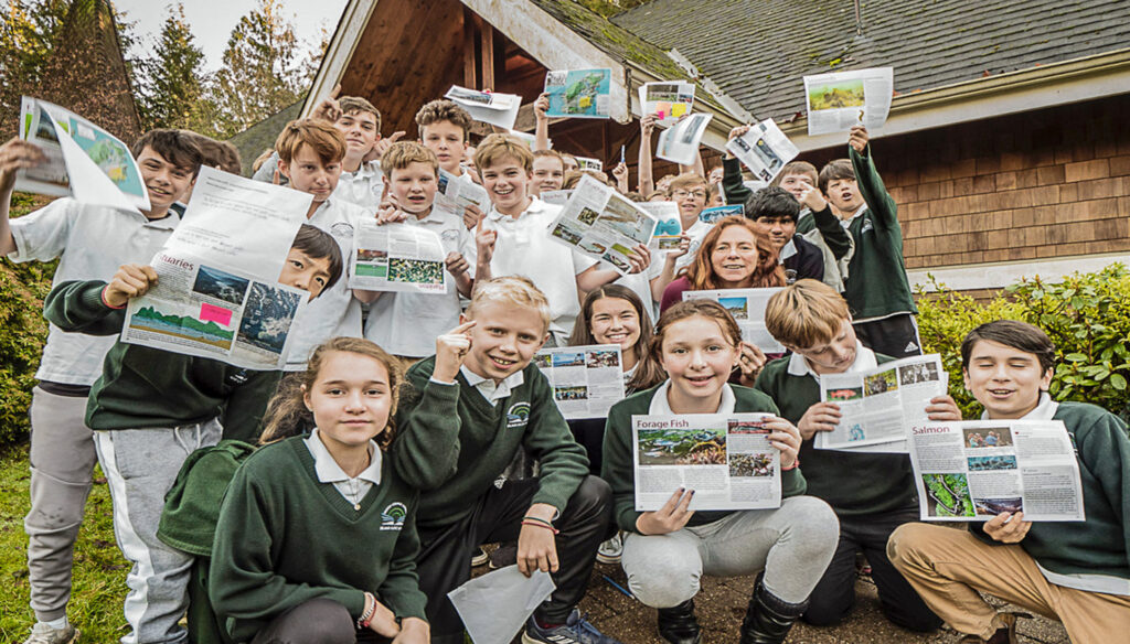 Kids at IPS and their teach Pam Matthews hold up brochures about forage fish for a class project.